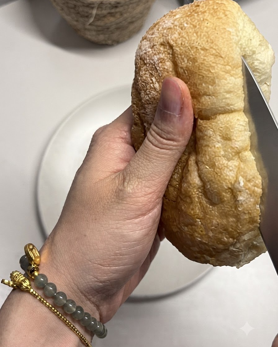 Une miche de pain ciabatta coupée en deux avec un couteau.
