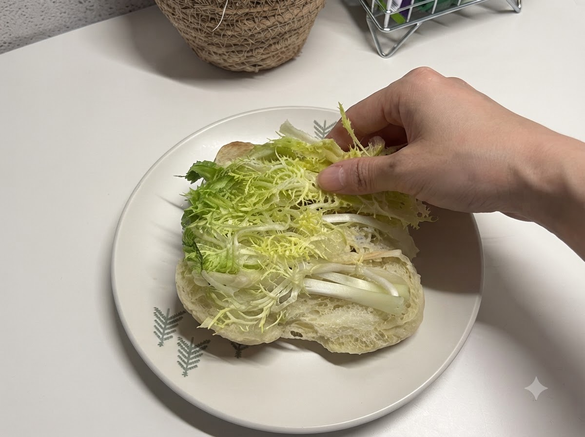 De la laitue fraîche émincée placée à lintérieur dun pain ciabatta ouvert.
