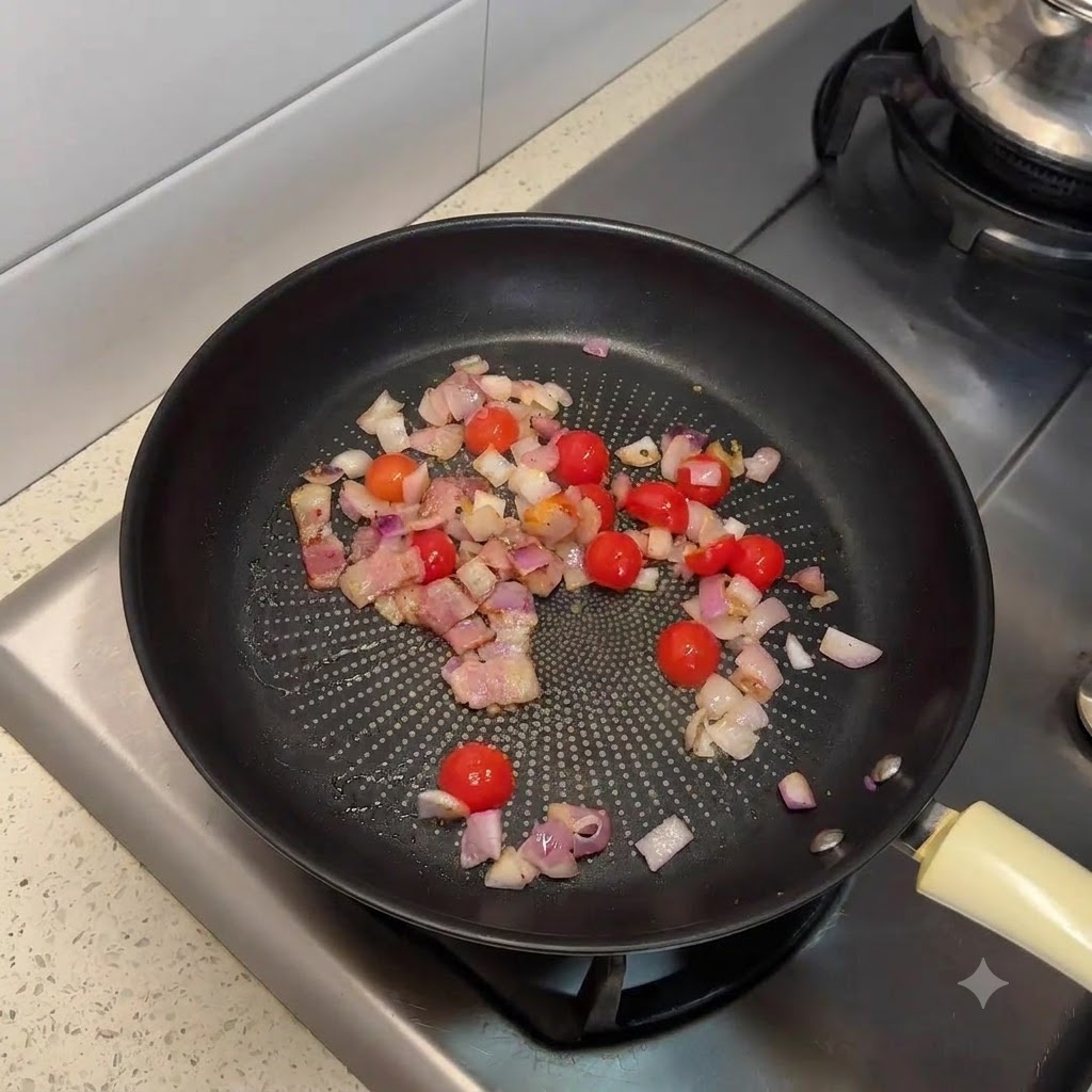 Une poêle remplie de bacon sauté, doignons hachés et de tomates cerises coupées en deux.