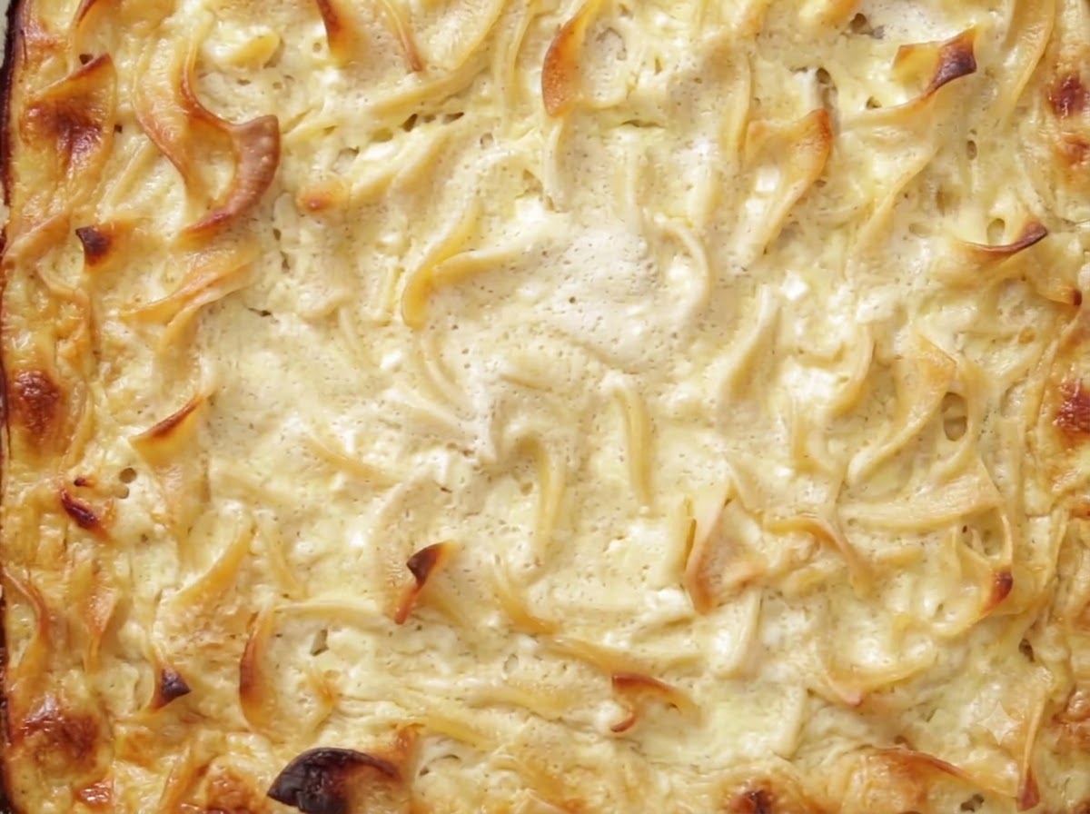 Un couteau coupant un kugel cuit et réfrigéré dans un plat en verre.