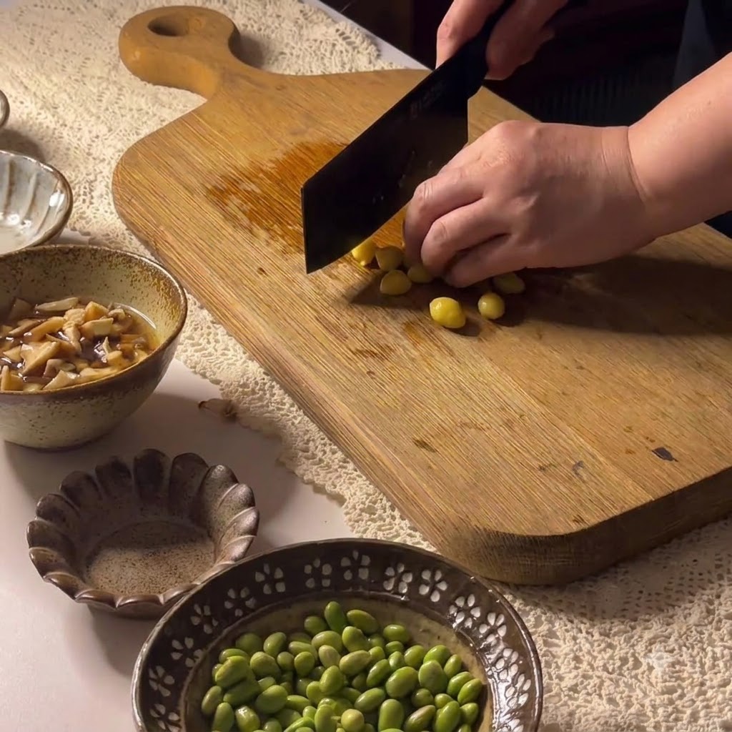 Noix de ginkgo coupées sur une planche à découper en bois avec un hachoir.