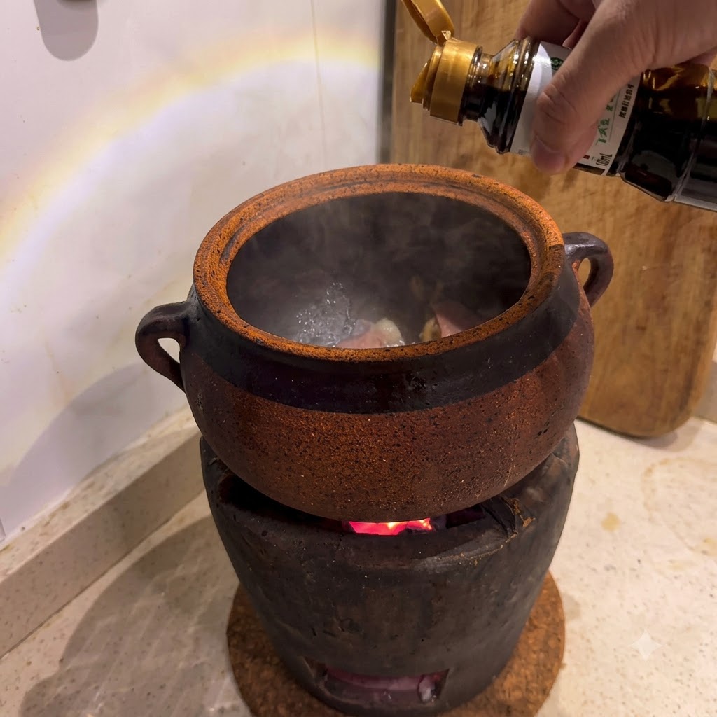 Sauce soja versée dune bouteille dans une cocotte en argile posée sur un poêle à charbon ardent.