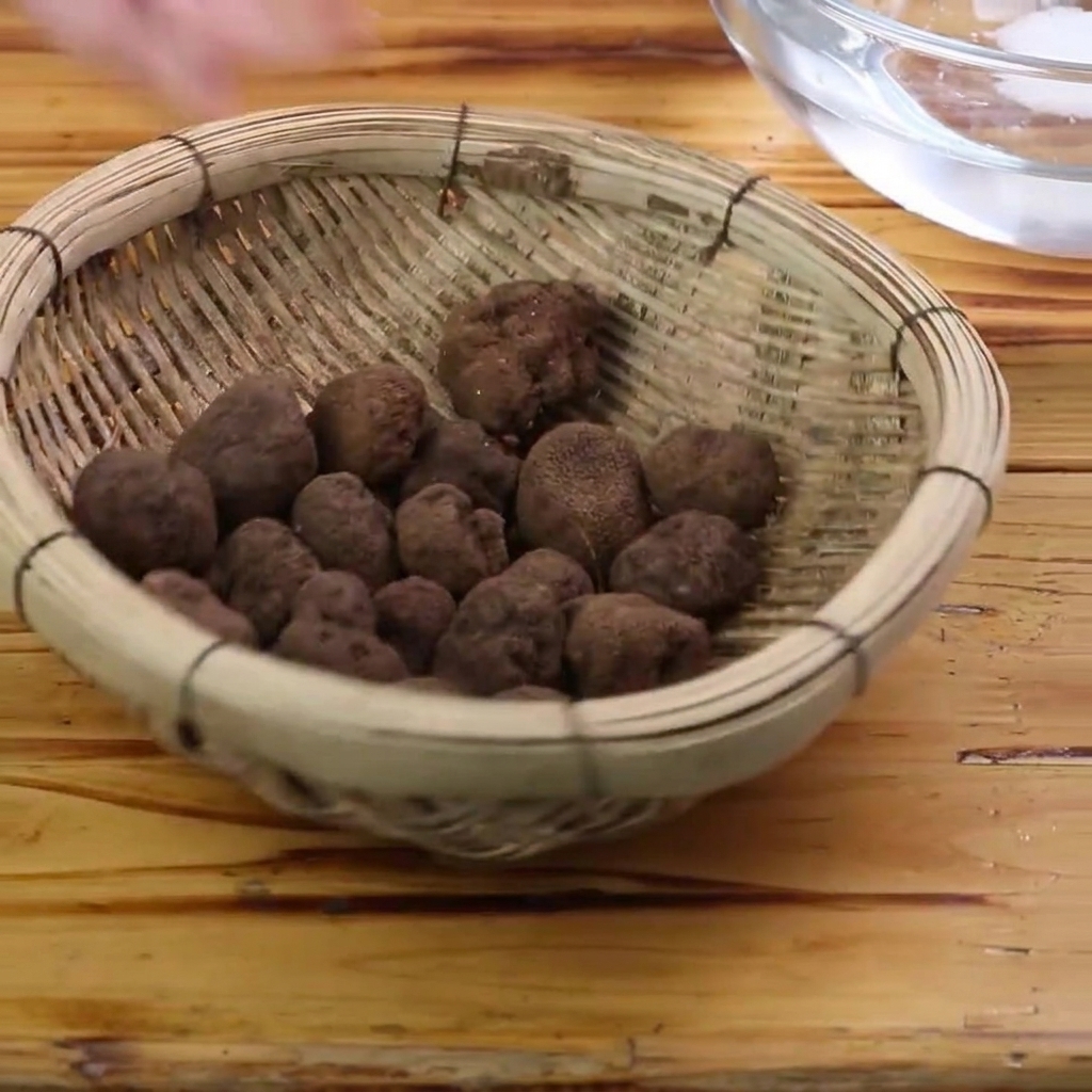 Truffes noires fraîches en train dêtre nettoyées avec une brosse dans un bol deau.