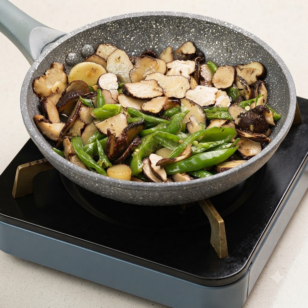 Une main saupoudrant du sel dans une poêle remplie de truffes tranchées et de poivrons verts en train de cuire.