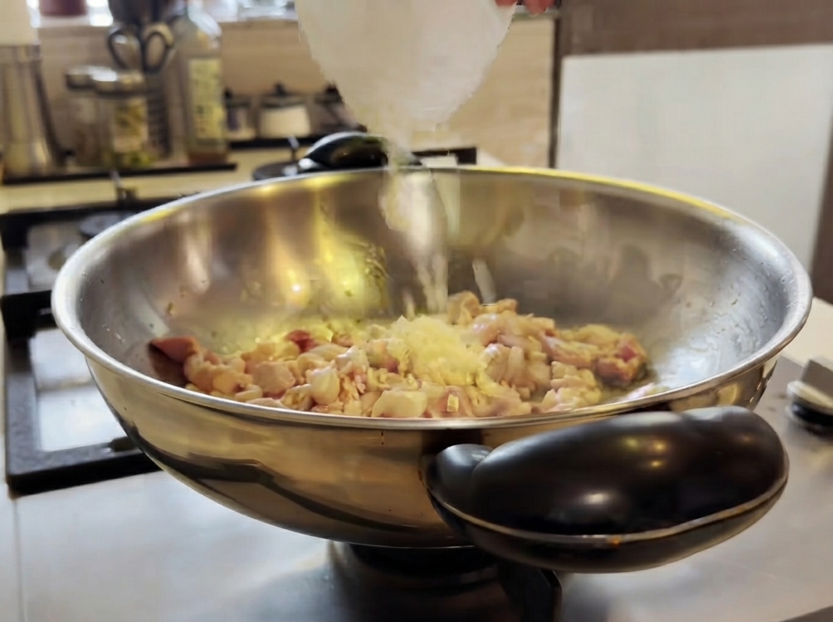 De lail haché ajouté dans un wok avec du poulet en cuisson et remué avec une spatule.