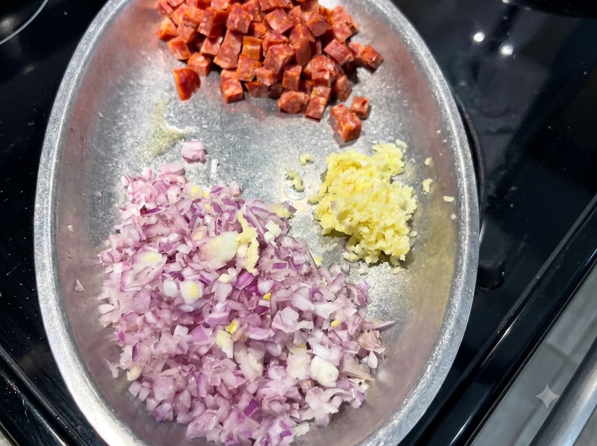 Une assiette en métal contenant des tas doignon rouge coupé en dés, dail haché et de cubes de chorizo espagnol.