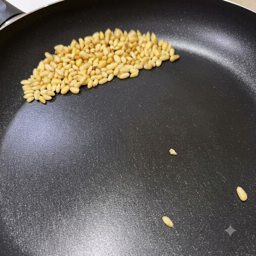 Pignons de pin dorant dans une poêle sèche lors de la préparation des spaghettis au pesto italien.