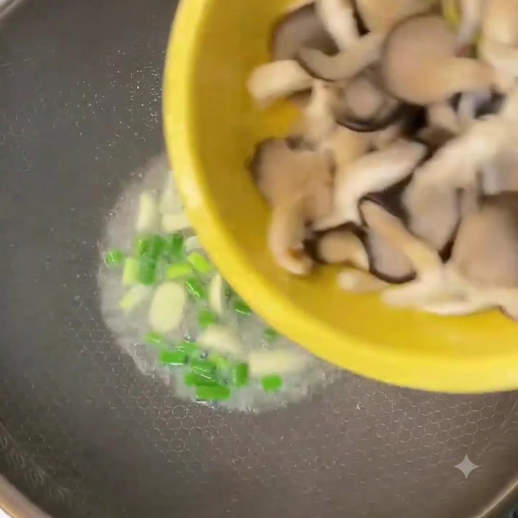 Des pleurotes hachés versés dun bol jaune dans un wok avec des oignons verts et de lail.