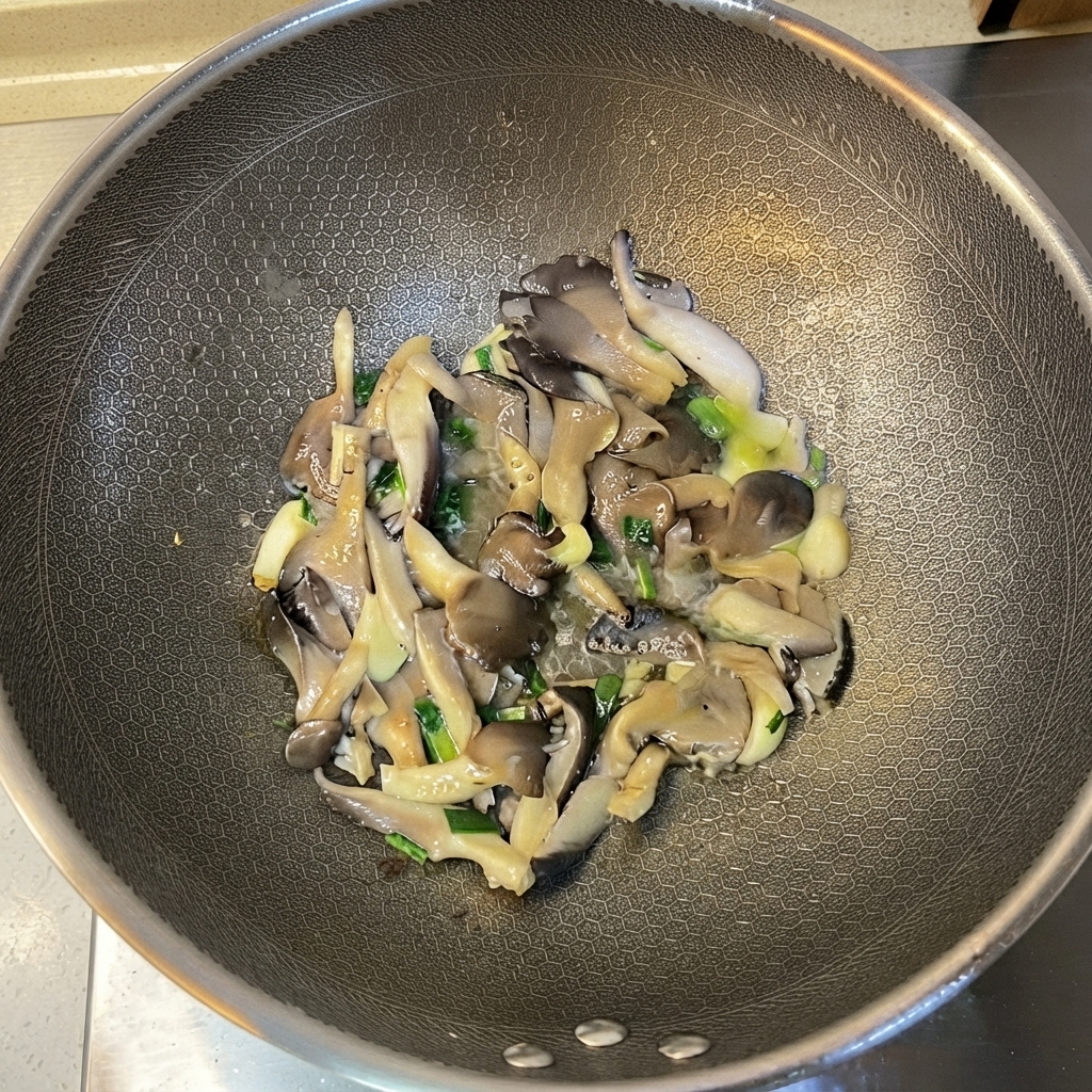 Des pleurotes cuits et des aromates mélangés à lintérieur du wok.