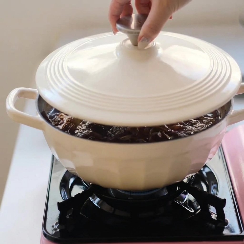 Une cocotte blanche couverte en train de mijoter sur un réchaud portable.