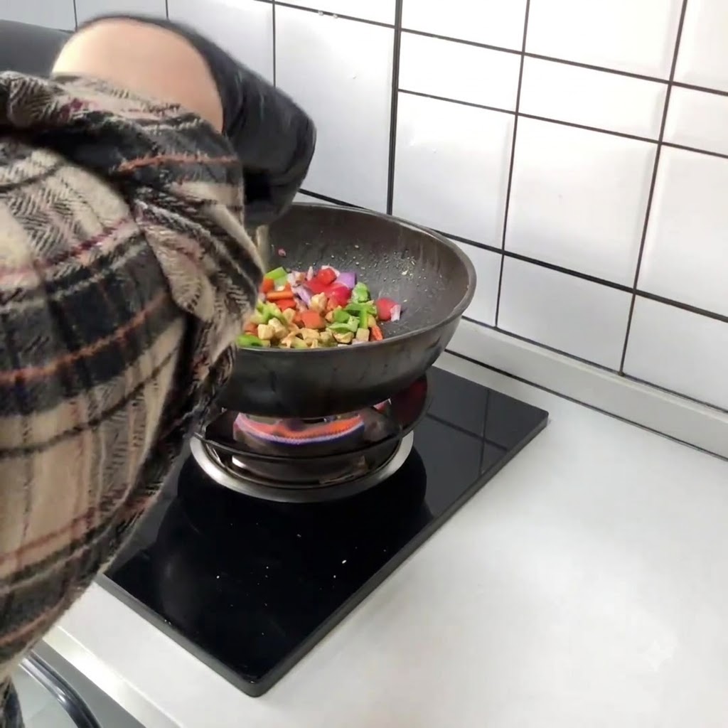 Poivrons rouges et verts hachés ajoutés directement dans le wok contenant le poulet sauté.