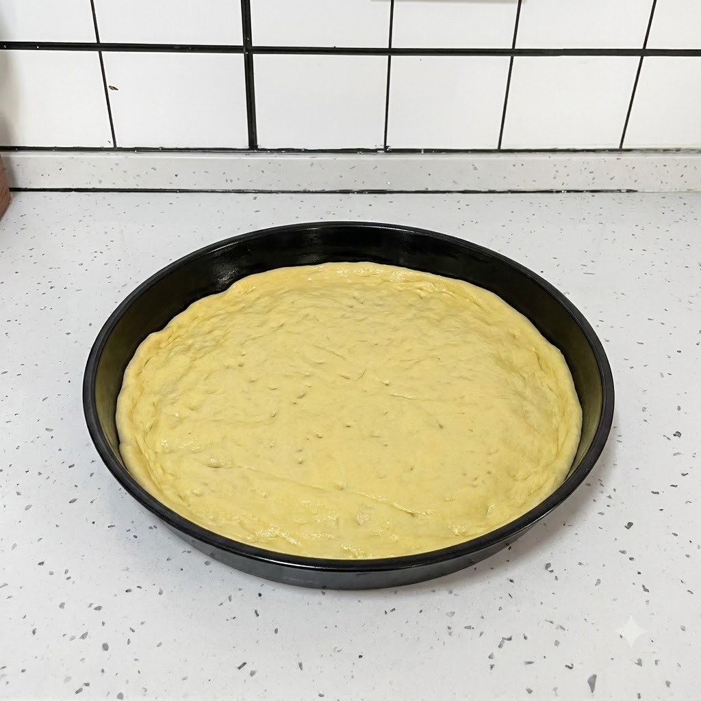 Un outil de cuisine noir utilisé pour percer de petits petits trous uniformément sur une pâte à pizza ronde et aplatie à lintérieur dun plat noir.