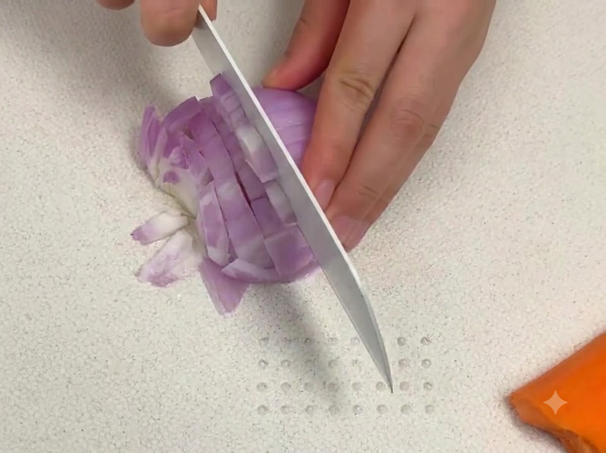 Un couteau bien aiguisé coupant des dés doignon rouge sur une planche à découper blanche à côté dun morceau de carotte.
