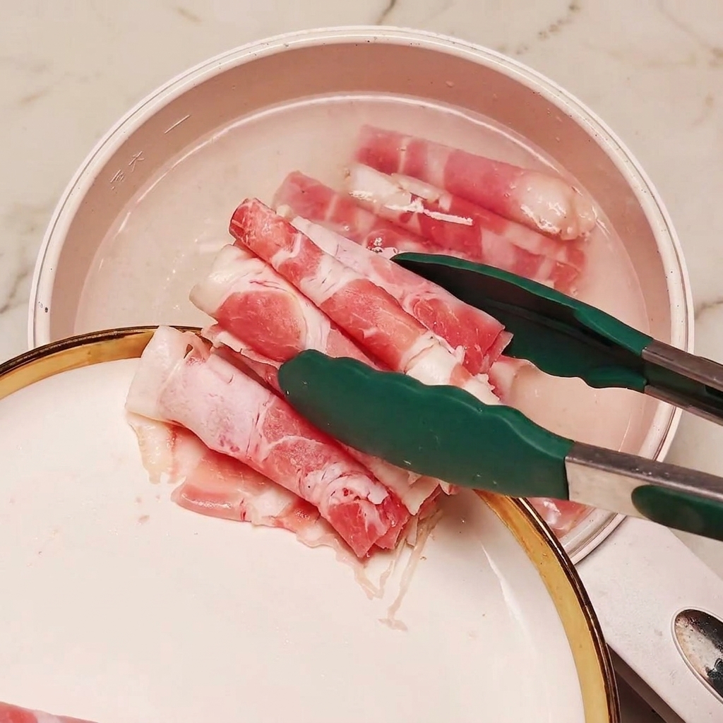Du bœuf émincé surgelé jeté dans une casserole deau bouillante avec des morceaux doignon vert à laide de pinces.