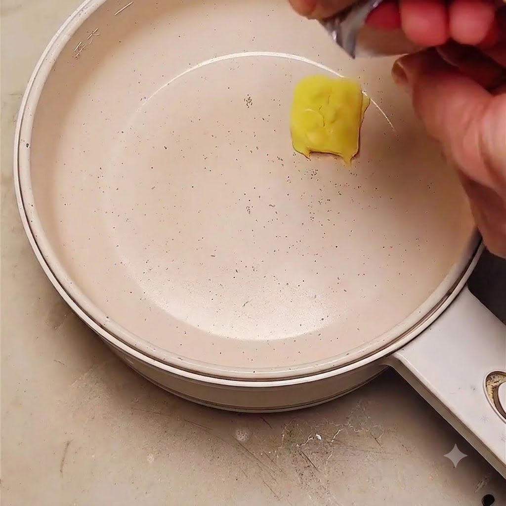 Une noix de beurre fondant dans une poêle avec des oignons rouges émincés ajoutés.