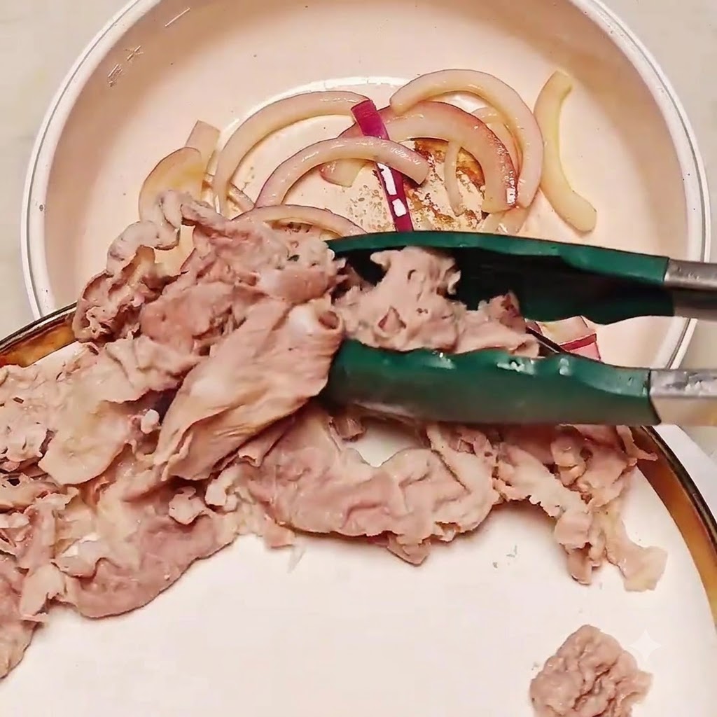 Des tranches de bœuf blanchies transférées avec des pinces dans une poêle contenant des oignons sautés.