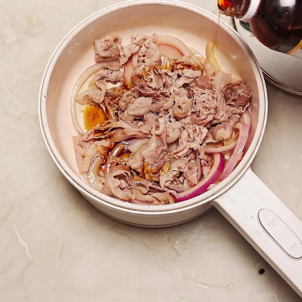 De la sauce sukiyaki versée dune bouteille dans une poêle remplie de bœuf et de tranches doignon rouge.