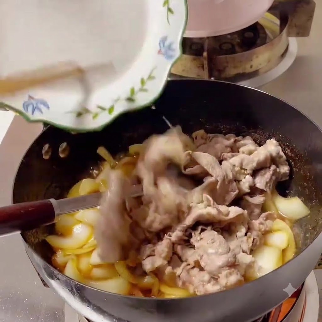 Des tranches de bœuf cuites glissées dune assiette blanche dans un wok rempli doignons et de sauce.