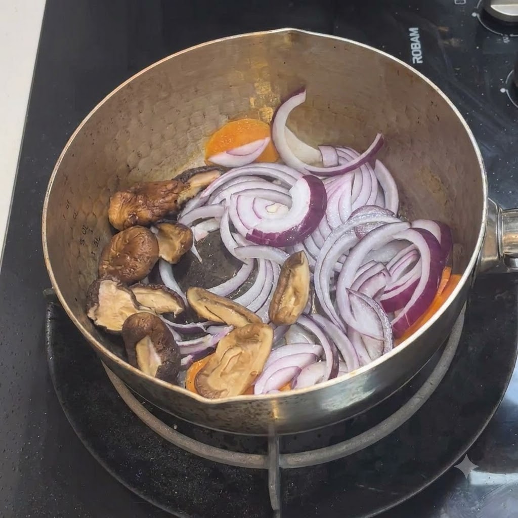 Des champignons shiitake tranchés placés à lintérieur de la casserole avec le mélange doignons et de carottes.
