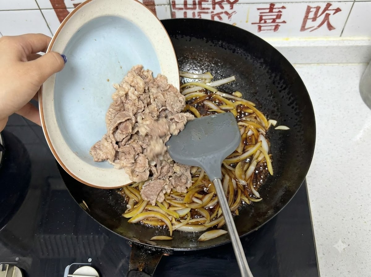 Des tranches de bœuf pré-blanchies versées dune assiette dans un wok avec des oignons et de la sauce foncée.