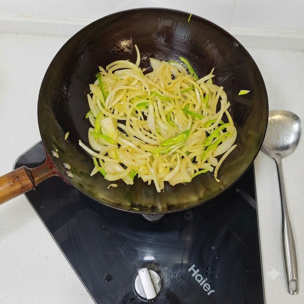 Des tranches doignons et de poivrons verts en train de sauter dans un wok noir chaud.