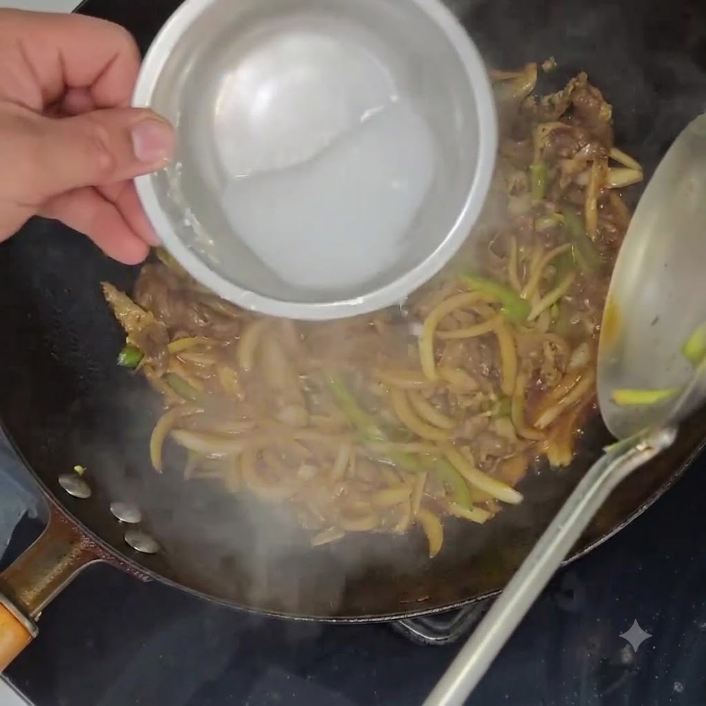 Un mélange de fécule de pomme de terre versé dun petit bol dans un wok rempli de bœuf et de légumes mijotés.