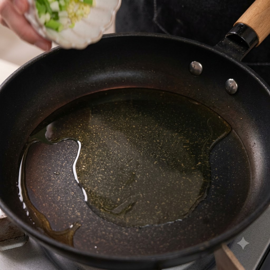 De lail haché et des morceaux doignons verts tombant dans une poêle contenant de lhuile chaude.