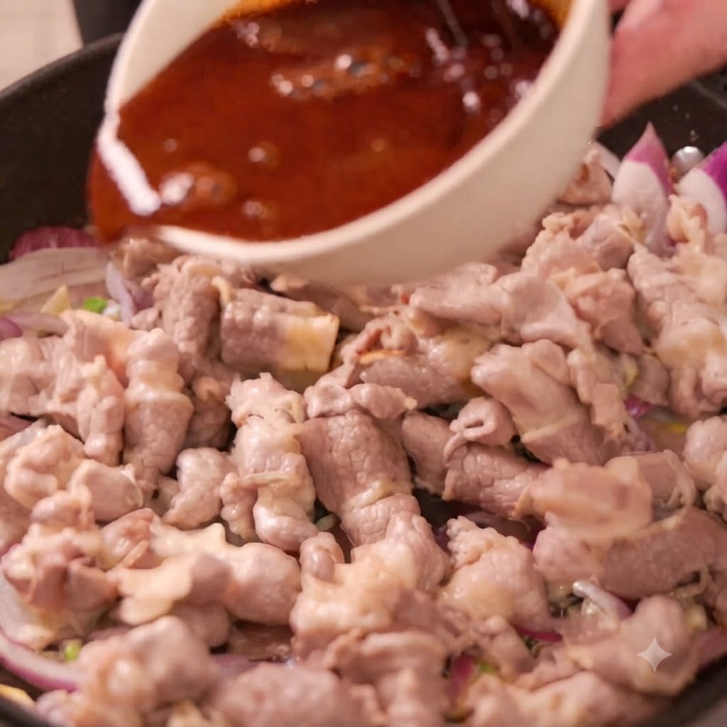 Un bol de sauce sombre versé dans une poêle remplie de rouleaux de bœuf et de tranches doignon rouge.