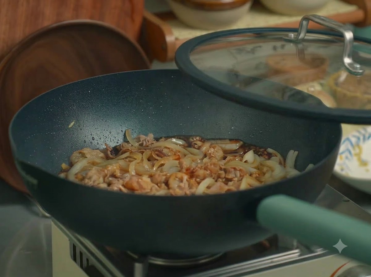 Une poêle remplie de bœuf et doignons recouverte dun couvercle en verre sur une cuisinière.