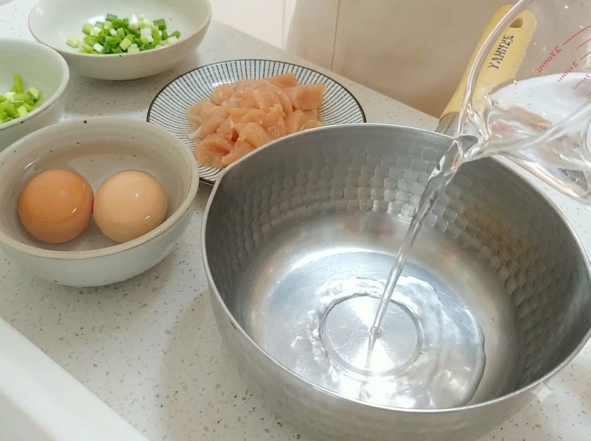 De leau claire versee dune tasse a mesurer dans une casserole en acier inoxydable.