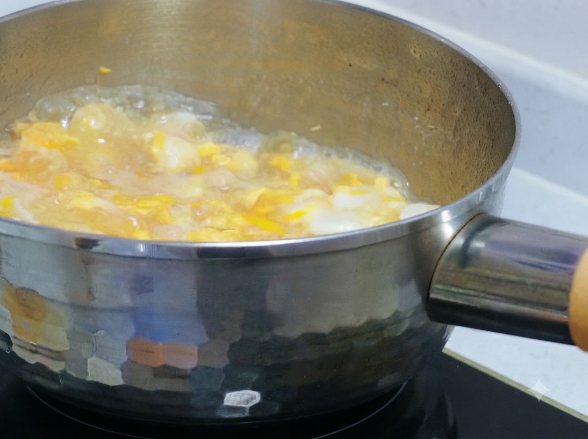 Du liquide doeuf partiellement battu verse sur du poulet et des oignons mijotant dans une casserole.