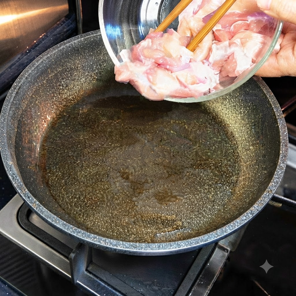Des morceaux de poulet cru versés dun bol en verre dans une poêle chaude et huilée.