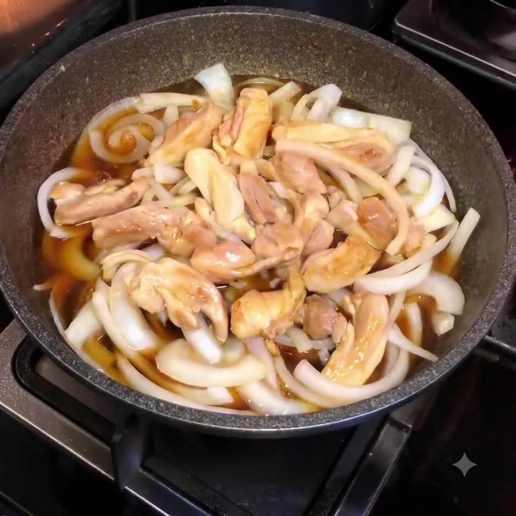 Une poêle remplie doignons émincés, de morceaux de poulet et de sauce brune, vue de dessus pendant le mijotage.