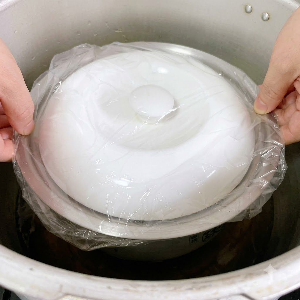 Le pot en métal scellé par du film plastique est abaissé avec précaution dans un grand autocuiseur.