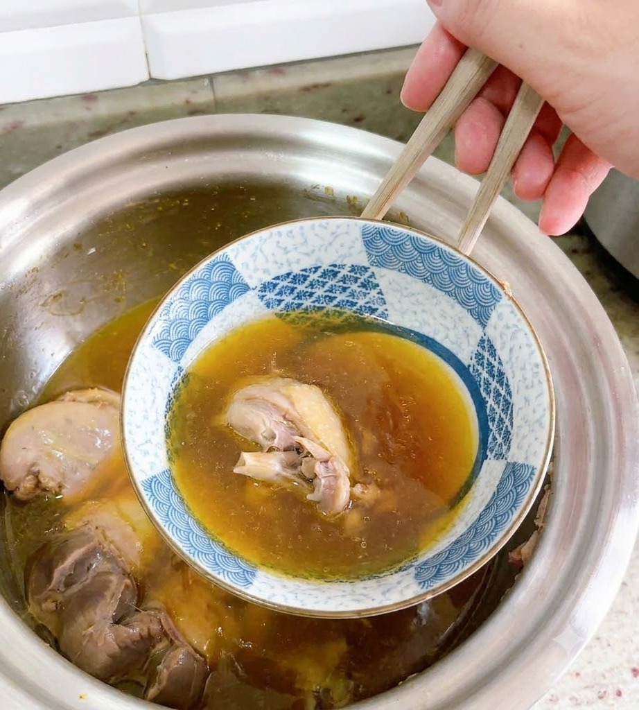 Un bol en céramique inversé est délicatement retiré de la soupe de canard à laide de baguettes.