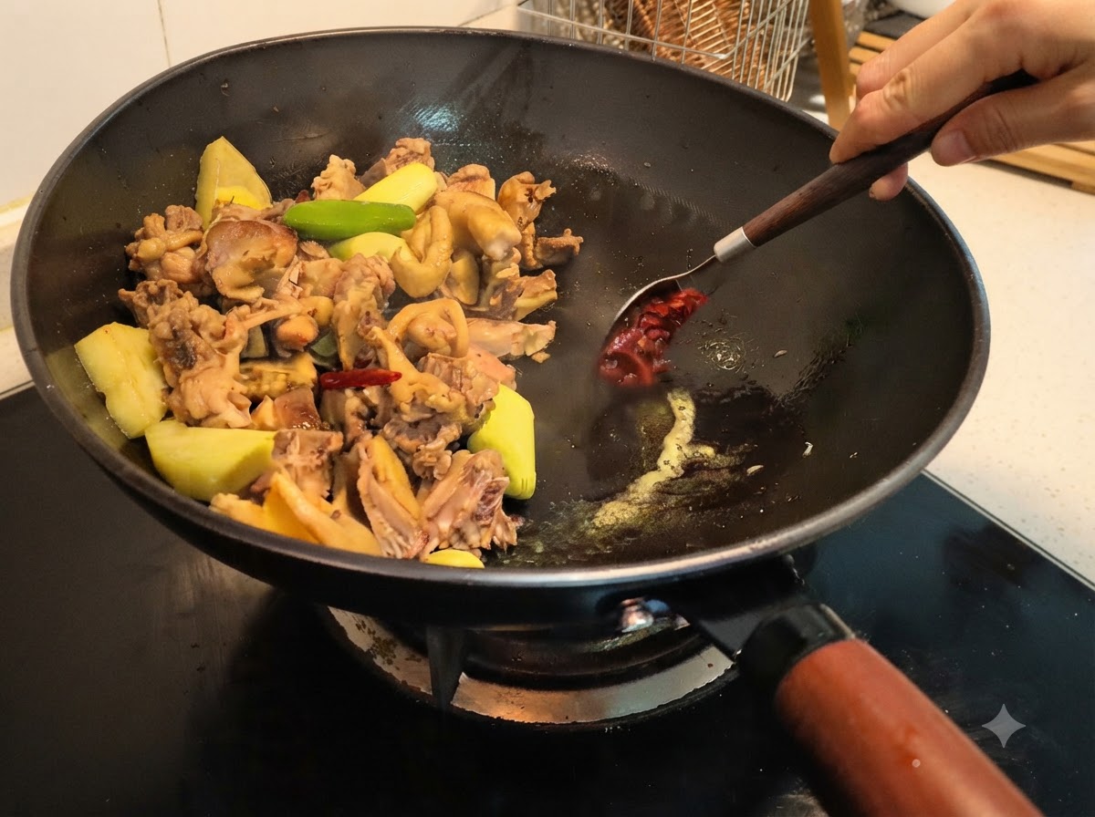 Pâte de fèves versée dans le wok et mélangée avec les ingrédients à laide dune cuillère.