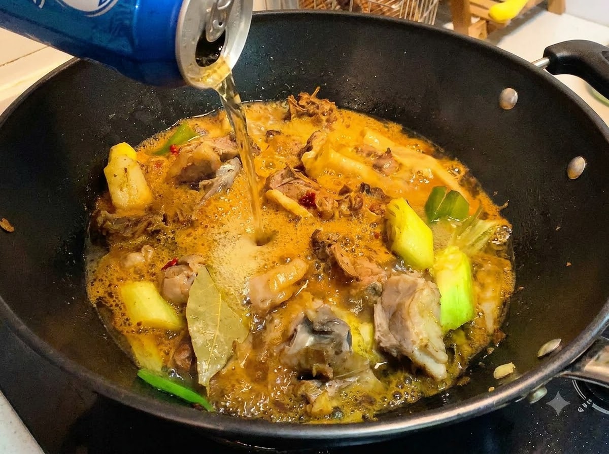 Une canette de bière versée dans un wok contenant des morceaux de canard cuits et une sauce riche et frémissante.