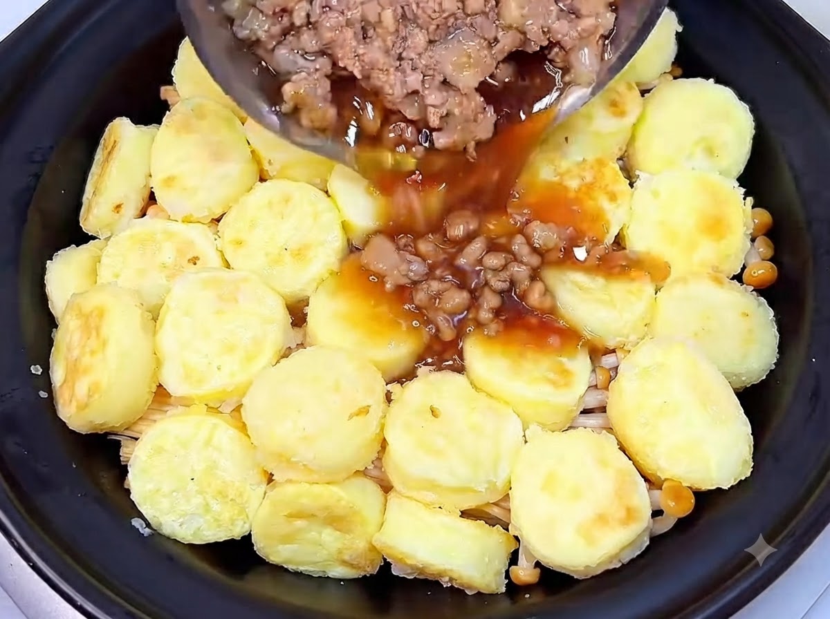 Porc haché cuit et sauce savoureuse foncée versés dune poêle sur la couche de tofu à lintérieur du plat en terre cuite.