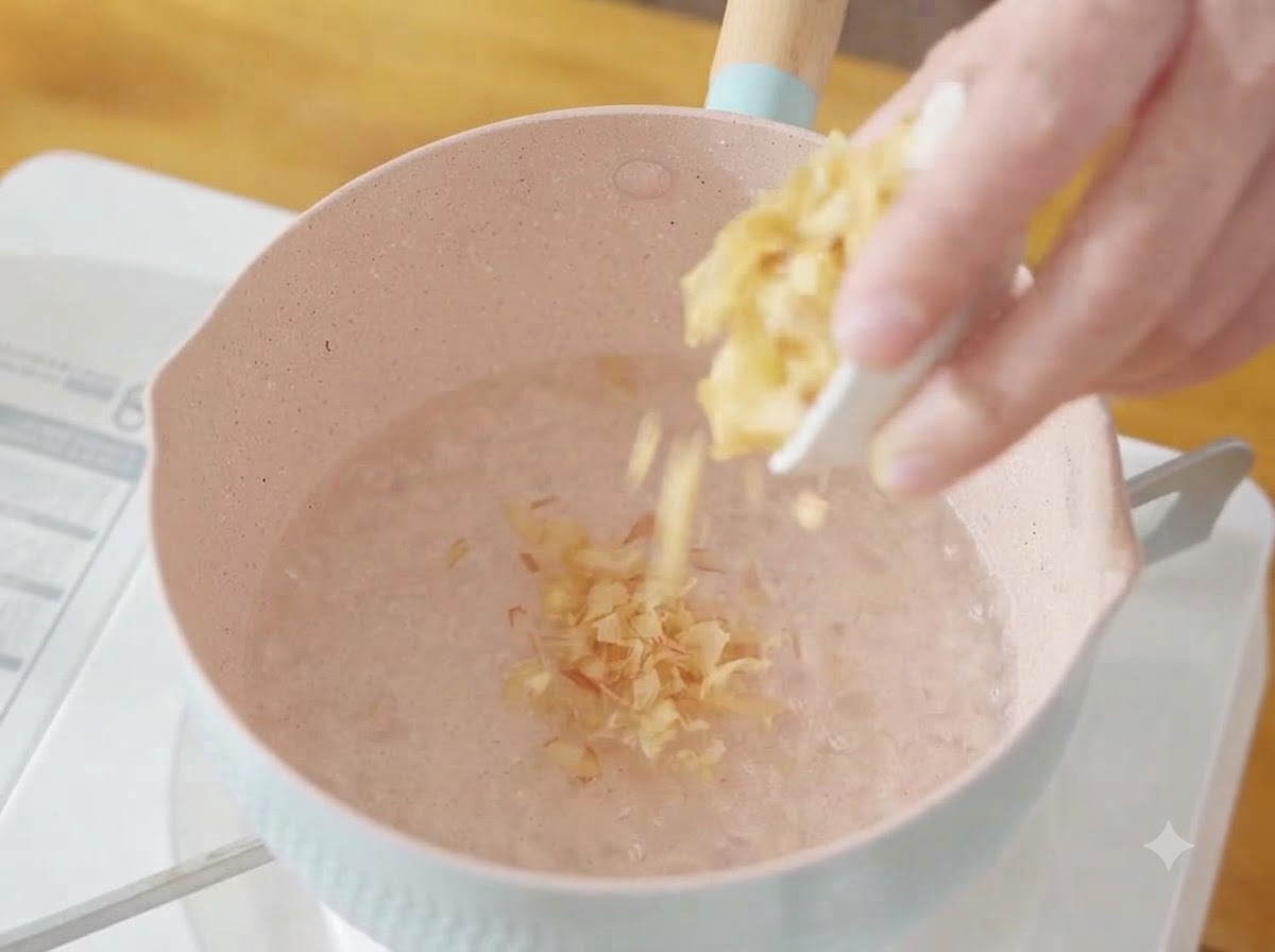 Une poignée de flocons de bonito secs jetés dans une casserole deau bouillante.