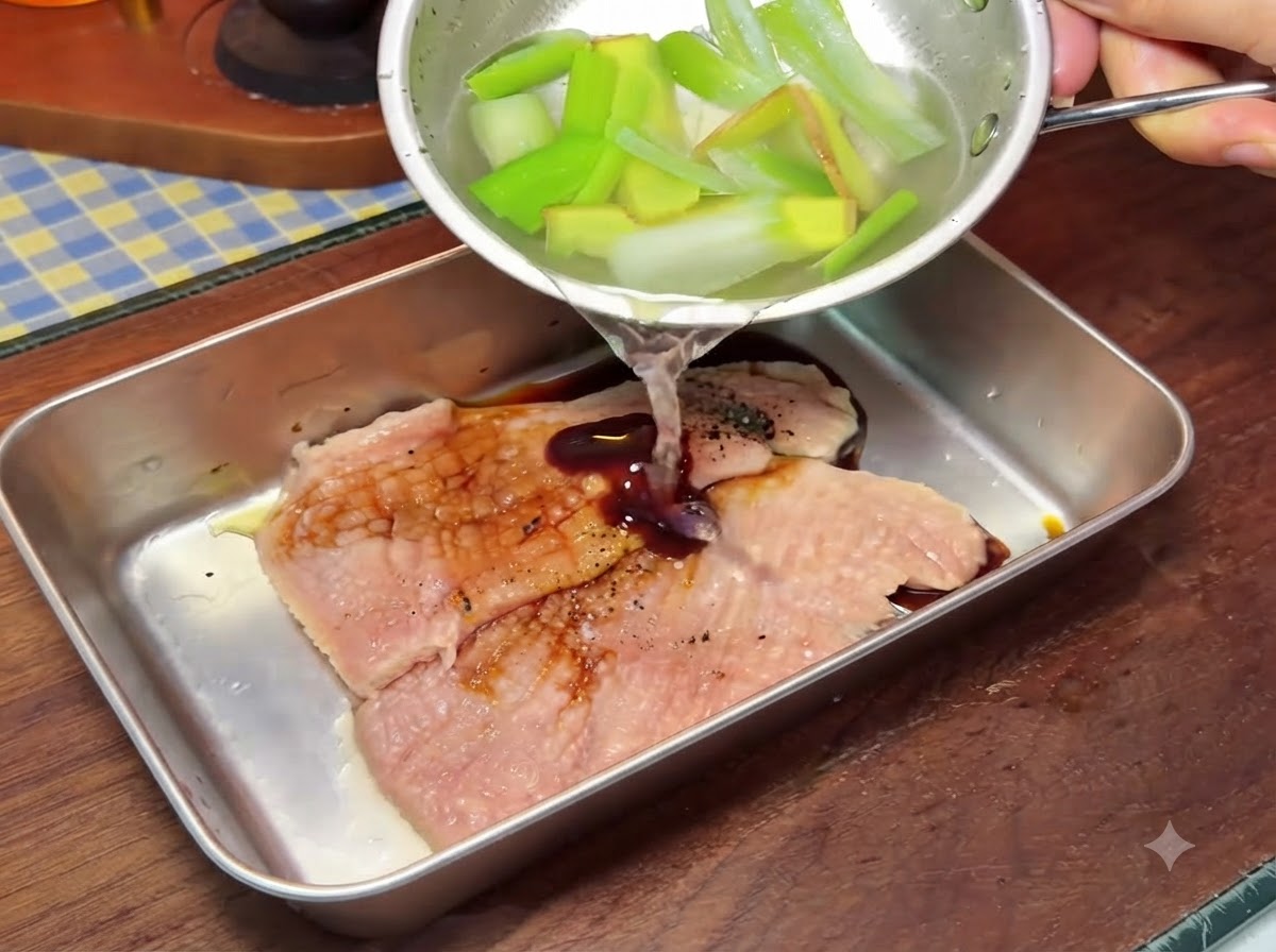 Un petit bol versant du liquide sur des côtelettes de porc à lintérieur dun plus grand récipient en métal pendant la préparation.