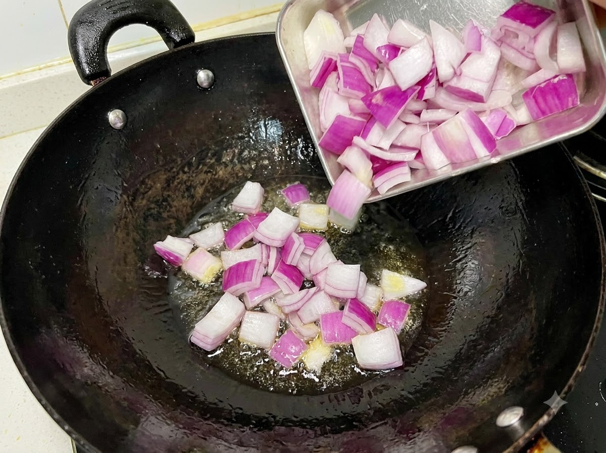 Des oignons rouges en dés grésillant et sautant dans un wok noir huilé.