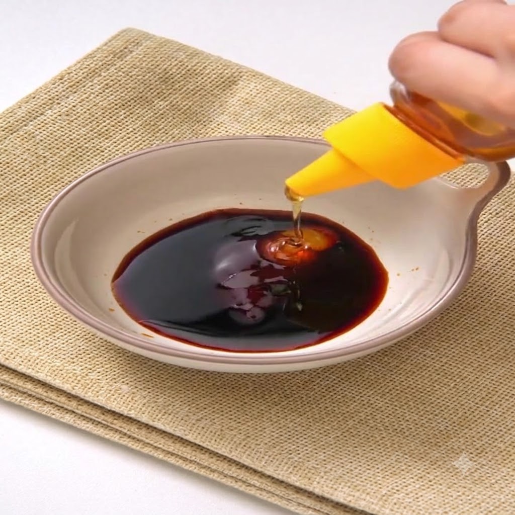 Du miel pressé depuis un flacon à bouchon jaune dans le mélange de sauce sombre à lintérieur dun bol en céramique.