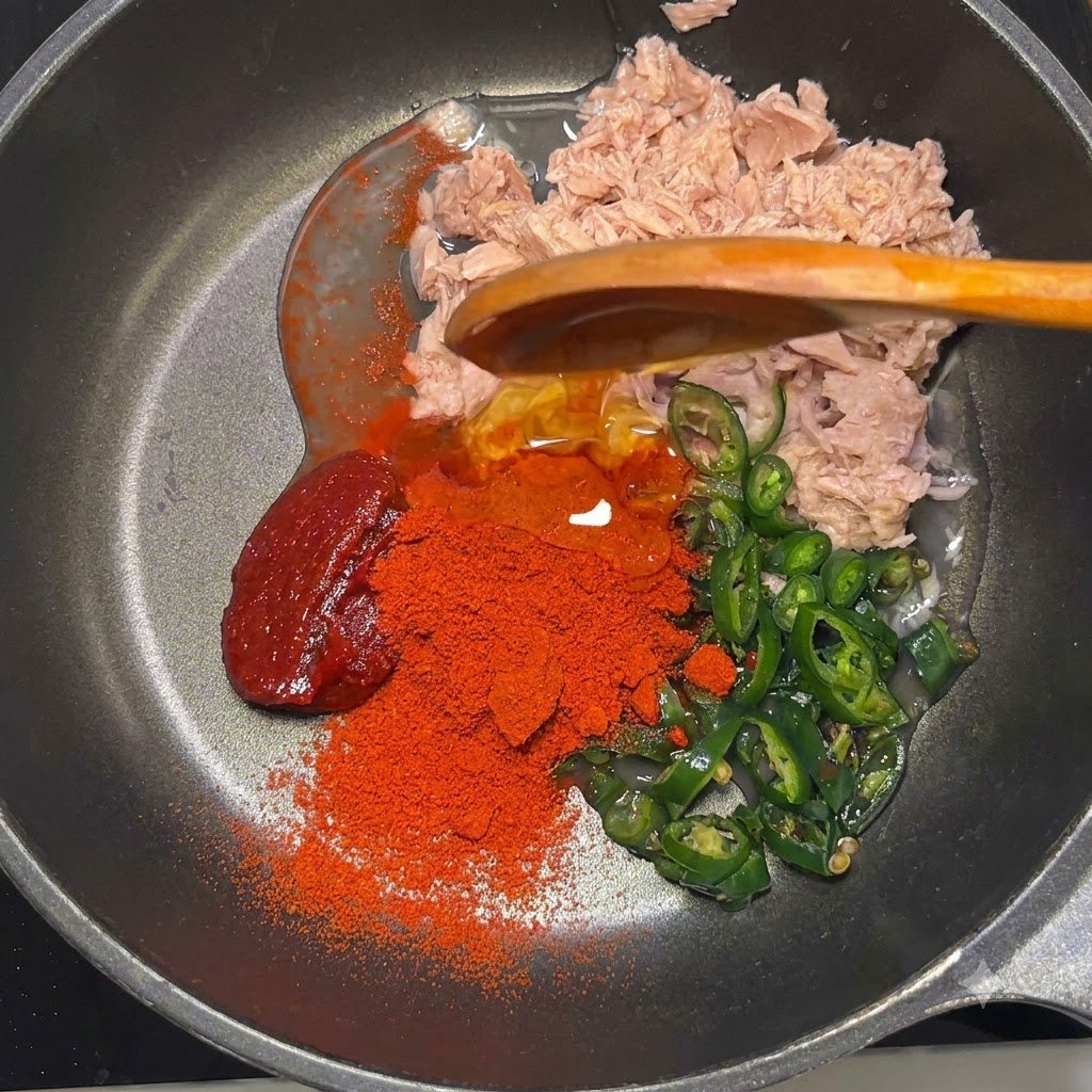 De la pâte de gochujang, de la poudre de gochugaru rouge, du sirop de maïs et de la mayonnaise dans la poêle.