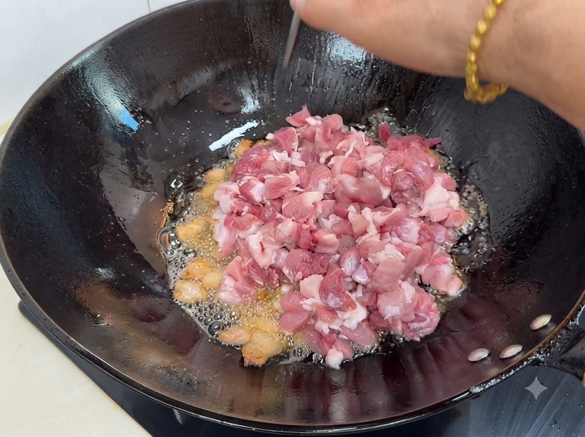 Morceaux de porc maigre frais en dés ajoutés dans le wok chaud avec le gras fondu et les épices.