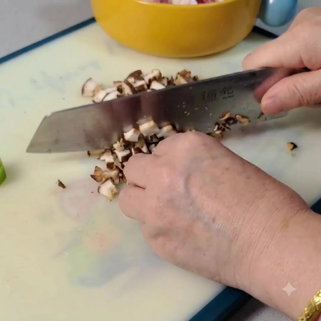 Des champignons shiitake crus en cours de tranchage et de hachage en petits morceaux sur une planche à découper.