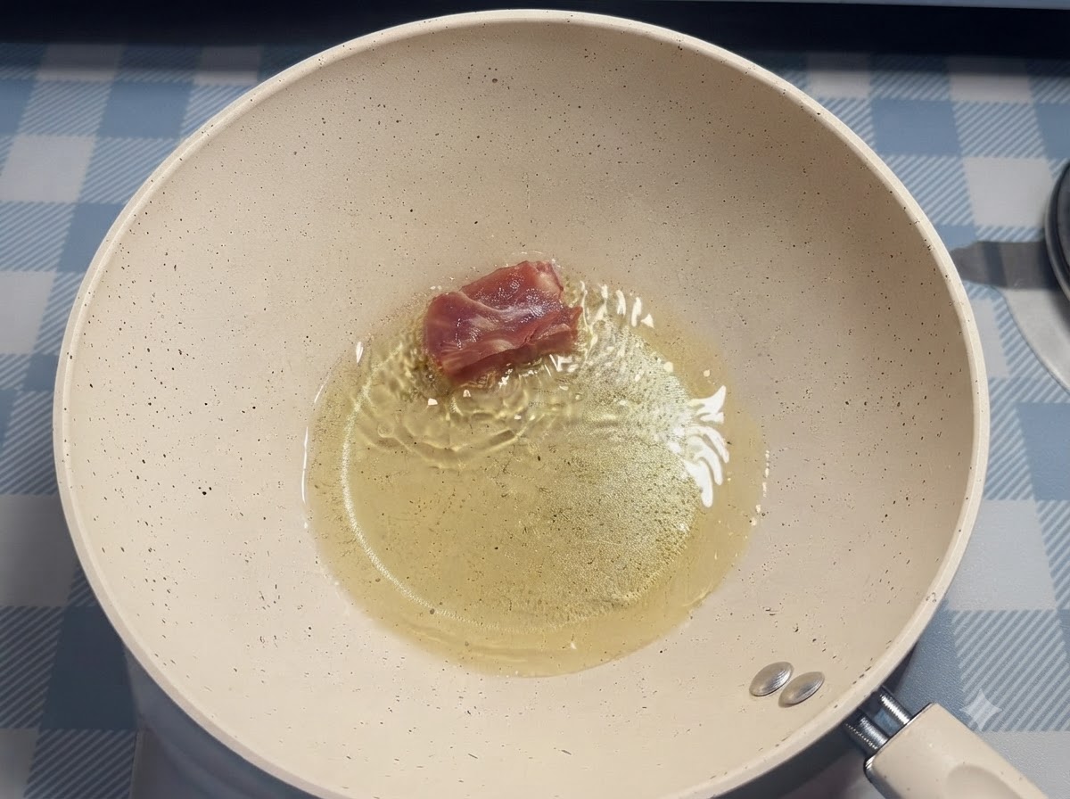 Un seul morceau de travers de porc déposé dans lhuile chaude dune poêle blanche à laide de baguettes.