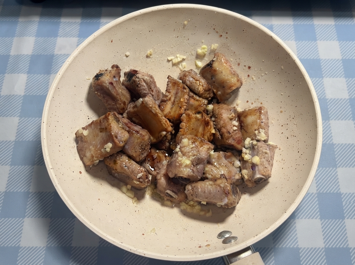 Travers de porc arrosés de sauce et de miel dans une poêle avant le mélange final.