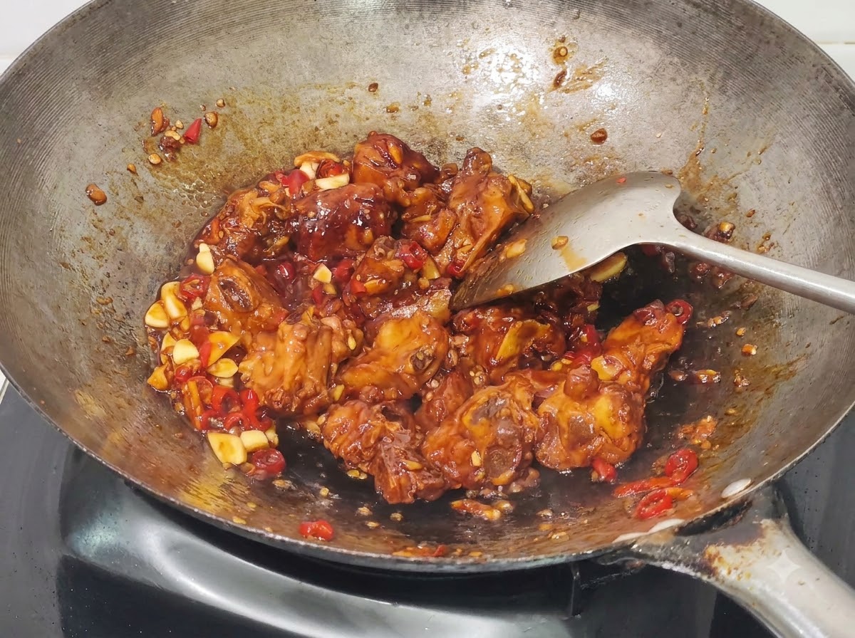 Ciboules hachées incorporées aux travers de porc au miel et à lail cuits dans le wok.