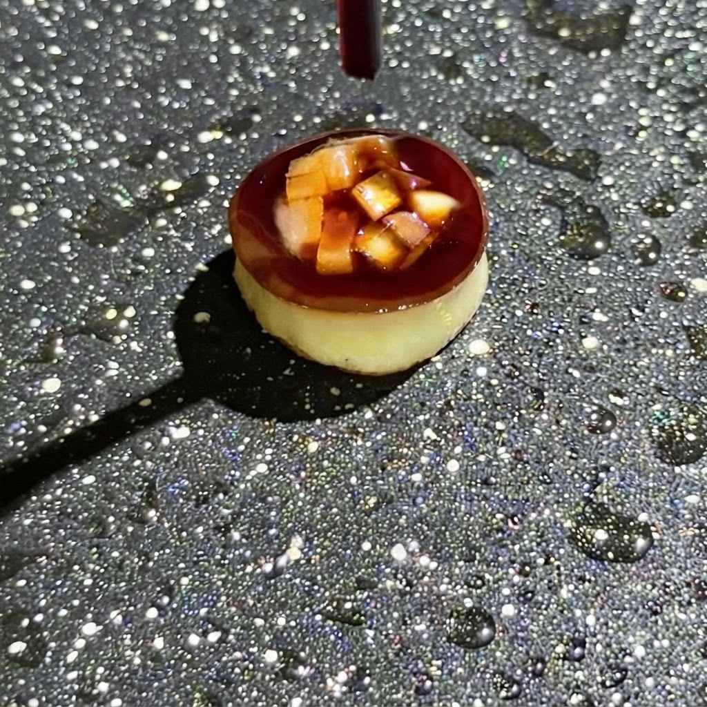Un compte-gouttes versant de la sauce soja foncée sur les ingrédients coupés en dés et farcis à lintérieur dun petit moule de cuisson rond dans une poêle.