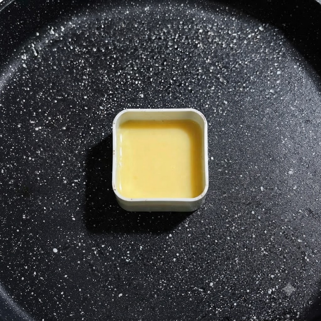 Un moule en métal carré rempli de liquide dœuf jaune reposant dans la poêle à frire, prêt pour le placement des ingrédients.